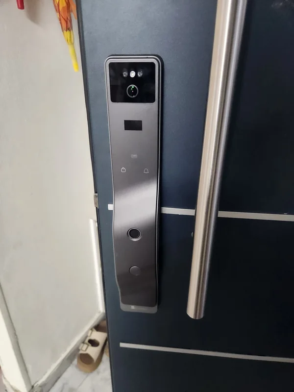 מנעול חכם בגוון כסוף בדלת שחורה לצד ידית משיכה ארוכה
