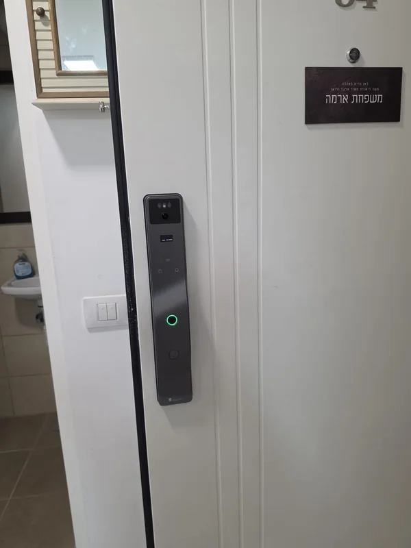 מנעול חכם כהה מותקן בדלת כניסה לבנה בבית